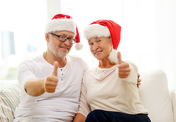 Image showing happy senior couple in santa helper hats at home