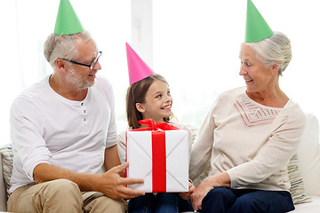 Image showing smiling family in party hats with gift box at home