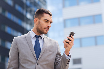 Image showing serious businessman with smartphone outdoors