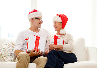 Image showing happy senior couple in santa hats with gift boxes