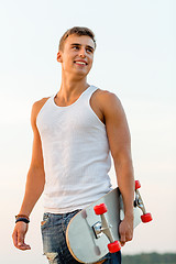 Image showing smiling teenage boy with skateboard outdoors