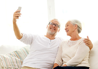 Image showing happy senior couple with smartphone at home