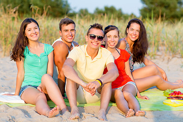 Image showing smiling friends sitting on summer beach