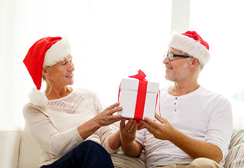 Image showing happy senior couple in santa hats with gift box