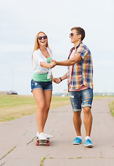 Image showing smiling couple with skateboard outdoors