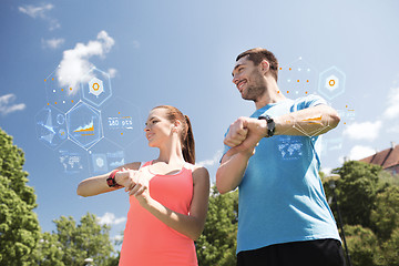 Image showing smiling couple with heart rate watches outdoors