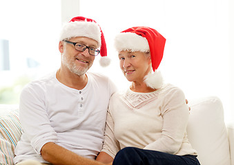 Image showing happy senior couple in santa helper hats at home