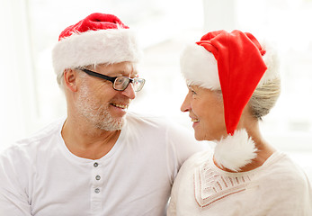 Image showing happy senior couple in santa helper hats at home