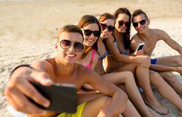 Image showing friends with smartphones on beach