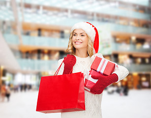 Image showing smiling young woman in santa helper hat with gifts