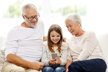 Image showing smiling family with smartphone at home