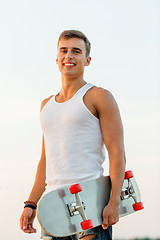 Image showing smiling teenage boy with skateboard outdoors