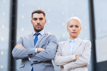 Image showing serious businessmen standing over office building