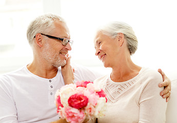 Image showing happy senior couple with bunch of flowers at home