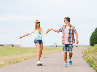 Image showing smiling couple with skateboard outdoors