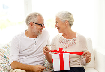 Image showing happy senior couple with gift box at home