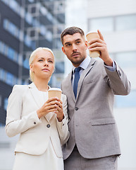 Image showing serious businessmen with paper cups outdoors