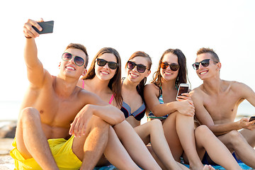 Image showing friends with smartphones on beach