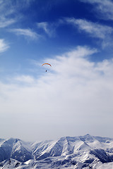 Image showing Sunlight mountain with clouds and silhouette of paraglider