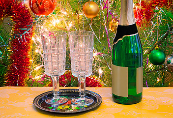 Image showing Christmas holiday, wine and glasses near a Christmas fir-tree.