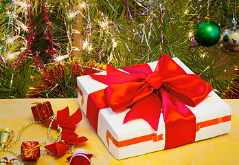 Image showing Beautifully packed gift by Christmas and the decorated fir-tree.
