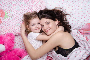 Image showing Mom hugs her daughter lying in bed