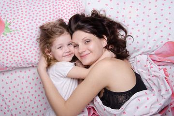 Image showing Mum embraces daughter lying in bed