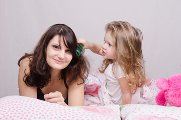 Image showing Girl combing her hair with enthusiasm mum