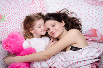 Image showing Mom and daughter happily resting in bed