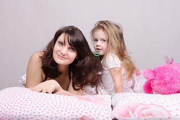 Image showing Mom and daughter with a hairbrush in her bed