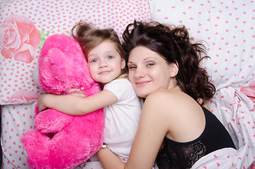 Image showing Mom hugs her daughter lying in bed