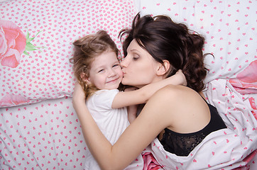 Image showing Mum kisses the daughter lying in bed