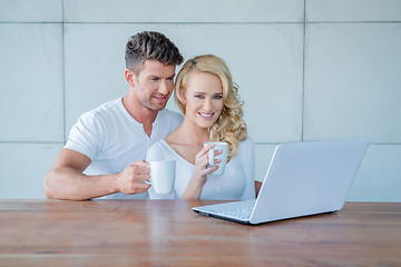 Image showing Couple drinking coffee and reading on a laptop
