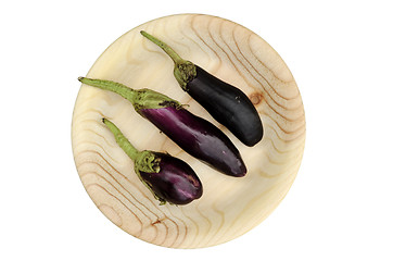 Image showing three eggplant on a round wooden plate