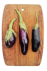 Image showing three eggplant on a wooden cutting board