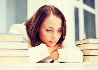 Image showing bored young woman with many books indoors