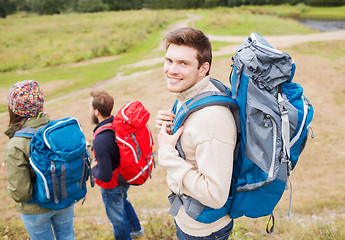 Image showing group of smiling friends with backpacks hiking