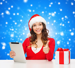 Image showing smiling woman in santa hat with gift and tablet pc