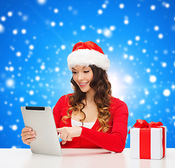 Image showing smiling woman in santa hat with gift and tablet pc