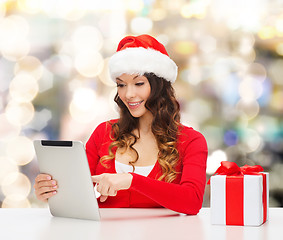 Image showing smiling woman in santa hat with gift and tablet pc