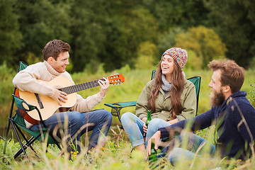 Image showing group of smiling friends with guitar outdoors