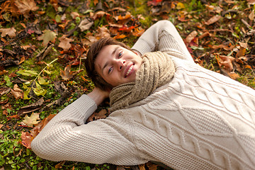 Image showing close up of smiling young man lying in autumn park