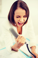 Image showing woman shouting into phone in office