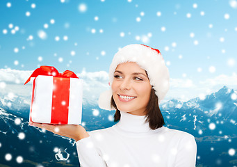 Image showing smiling woman in santa helper hat with gift box