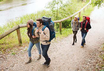 Image showing group of smiling friends with backpacks hiking