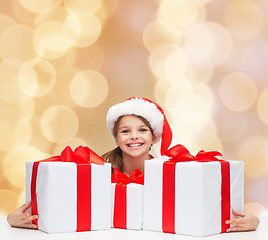 Image showing smiling girl in santa helper hat with gift boxes