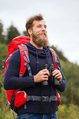 Image showing smiling man with backpack and binocular outdoors