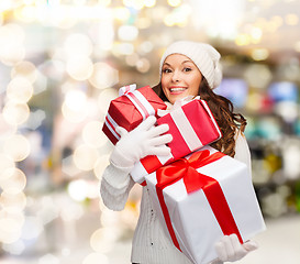 Image showing smiling young woman in santa helper hat with gifts
