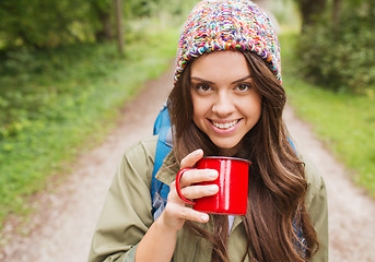 Image showing smiling young woman with cup and backpack hiking