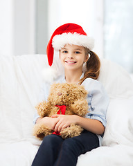 Image showing smiling girl in santa helper hat with teddy bear